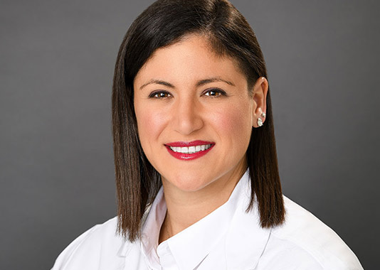 Professional headshot of orthopedic nurse practitioner Christina Coppola, AGPCNP-BC, smiling in white lab coat.