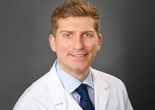Professional headshot of orthopedic surgeon Dr. Adel Mahjoub, MD, smiling in white lab coat.