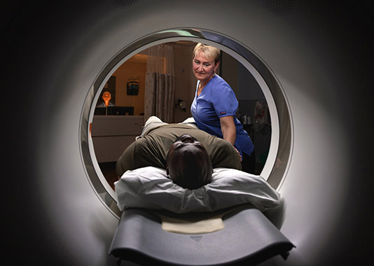 A medical radiology technician supports a patient with a construction OTJ injury as he prepares for an MRI scan.