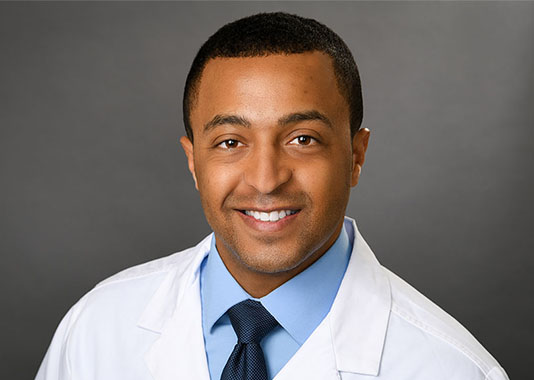Professional headshot of orthopedic surgeon Dr. Kyle Angelicola-Richardson, MD, smiling in white lab coat.