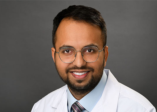 Professional headshot of orthopedic surgeon Dr. Imran Akhtar, DO, smiling in white lab coat and glasses.
